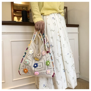 Detail view of a handmade knit tote bag with colorful 3D crochet flowers and strap