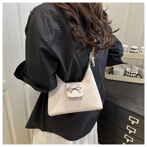 Détail du sac tressé blanc avec boucle nœud papillon en métal argenté et bandoulière
