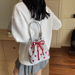 Silver bucket bag with red heart embroidery and drawstring closure shown in home setting
