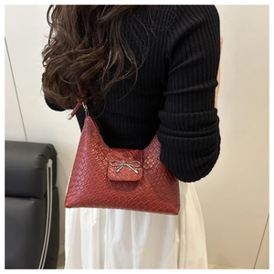 Détail du sac à bandoulière tressé rouge foncé avec boucle en forme de nœud