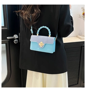 Detail of light blue crossbody bag with contrast denim flap and gold flower lock