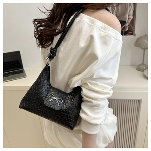 Détail du sac croissant noir tressé avec nœud argenté et bandoulière à nœud élégant