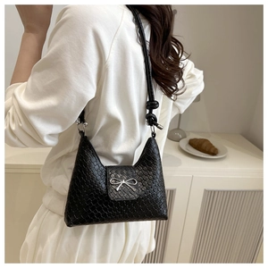 Detailed macro view of woven texture and silver bow buckle on black shoulder bag