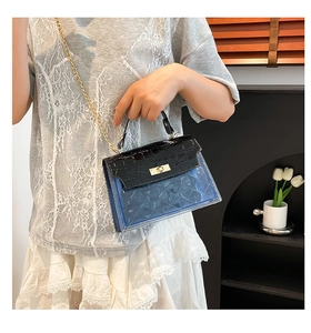 Detail of blue transparent PVC bag with black croc-embossed flap and gold twist lock