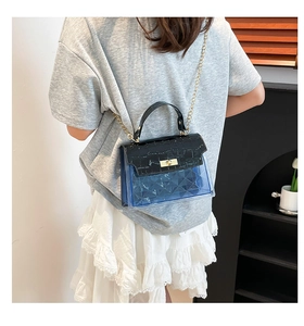 Detail of a color-block Kelly bag with blue PVC body and black croc-textured leather flap