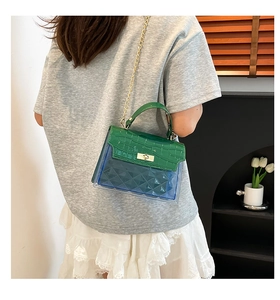 Detail of green croc-embossed flap and gold twist-lock on a stylish crossbody bag