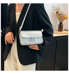 Détail du sac à bandoulière argenté avec texture pailletée et boucle métallique CD