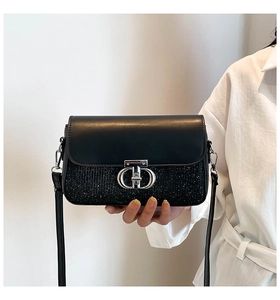 Détail du sac à bandoulière noir avec fermoir en métal argenté et texture pailletée