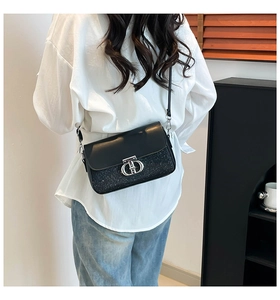 Détail d'un sac bandoulière noir avec boucle argentée et empiècement scintillant