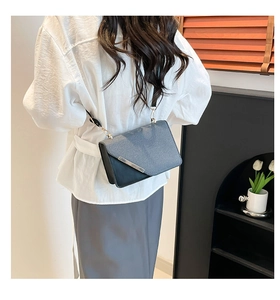 Détail d'un sac bandoulière élégant en cuir gris et noir avec garniture métallique et crochet doré