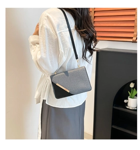 Sac bandoulière carré pour femme avec barre dorée porté par un mannequin pour l'échelle