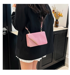 Vue détaillée d'un sac bandoulière rose avec rabat asymétrique et bordure dorée