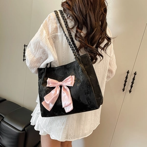 Black suede tote bag with pink satin bow and woven leather handles shown on model