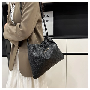 Détail du sac bandoulière tissé noir avec logo en métal doré et cordon de serrage