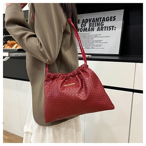 Détail du sac à bandoulière tressé rouge foncé avec cordon de serrage et logo doré
