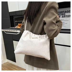 Détail du sac seau tissé blanc avec fermeture à cordon porté à l'épaule par le mannequin