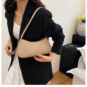 Detail of light beige baguette bag with elegant gold bow hardware and leather texture