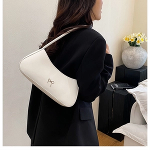 Nahaufnahme einer weißen Leder-Schultertasche mit silberner Schleife an einem Model