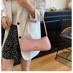 Pink shoulder bag with silver bow detail shown on a model in a French chic style