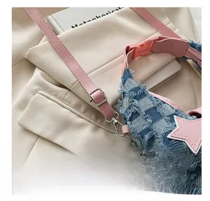 Dettaglio della fibbia rosa regolabile e patch a stella su borsa in denim a scacchi