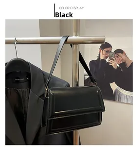 Detalle de bolso bandolera de cuero negro con solapa y costuras refinadas en los bordes