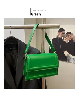 Detalle del bolso bandolera verde brillante con herrajes dorados y solapa rectangular
