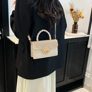 Cream white underarm bag with woven flap, twisted handle and gold flower buckle