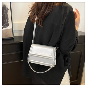 Bolso bandolera plateado brillante visto desde atrás sobre ropa negra muy elegante