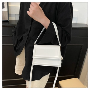 Detalle de bolso bandolera blanco minimalista con textura horizontal y correa fina