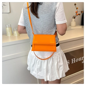 Bolso cuadrado pequeño en color naranja vibrante llevado al hombro en ambiente moderno