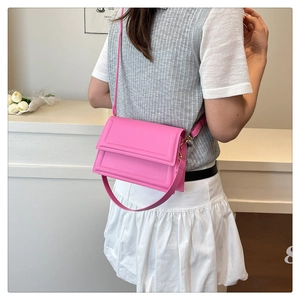Detalle de bolso bandolera rosa vibrante con marco geométrico grabado y acabado de cuero mate