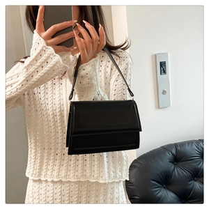 Bolso bandolera negro minimalista con solapa mostrado en un selfie de espejo de estilo
