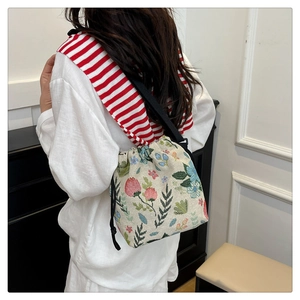 Detail of floral embroidery on a cream linen bucket bag with black drawstrings