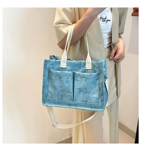 Detail of light blue tote bag with bamboo print, dual front pockets and canvas strap