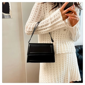 Detalle del bolso bandolera de cuero negro con acabado suave y herrajes dorados claros