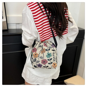Detail of vintage floral canvas bucket bag with drawstring closure shown on model