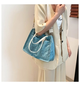 Close-up of blue tote bag with bamboo leaf print featuring white handles and adjustable strap