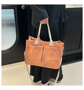 Detail of orange tote bag with bamboo print featuring dual front pockets and woven handles