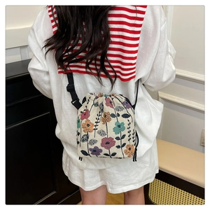 Detail of drawstring floral bucket bag with colorful brocade patterns and adjustable strap