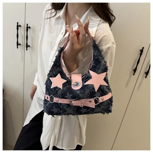 Dettaglio di stelle rosa e fibbie punk su borsa a tracolla in denim blu vintage