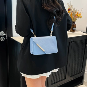 Petit sac carré bleu clair bandoulière avec garniture métallique porté par un mannequin