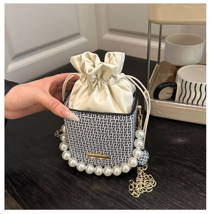 Detail of elegant drawstring box bag with large pearl handle and luxury metal chain strap