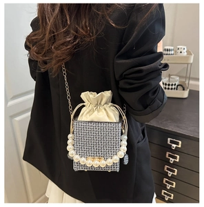 Detail of crossbody bucket bag with pearl handle and geometric pattern on a model