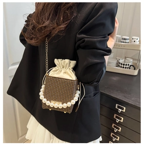 Detail of vintage box bag with geometric monogram pattern, pearl handle and gold chain