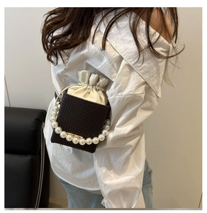 Detail of mini box bag featuring brown woven texture and pearl handle worn by model