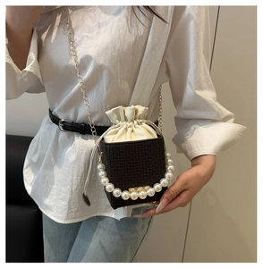 Detail of dark brown mini bucket bag featuring a large pearl handle and woven texture