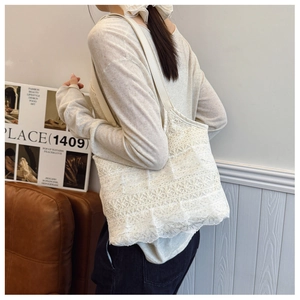 Detail of white lace tote bag featuring multi-layered floral embroidery and slim strap