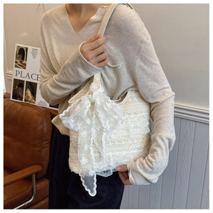 Close-up of elegant cream lace handbag with large floral bow and leather shoulder strap