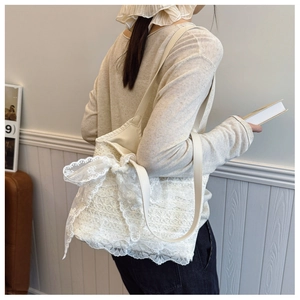 Detail of white lace tote bag featuring 3D floral textures and a large side bow detail