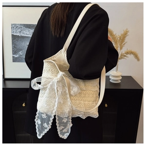 Detailed lace texture and bow accent on a cream crochet bucket bag worn by model